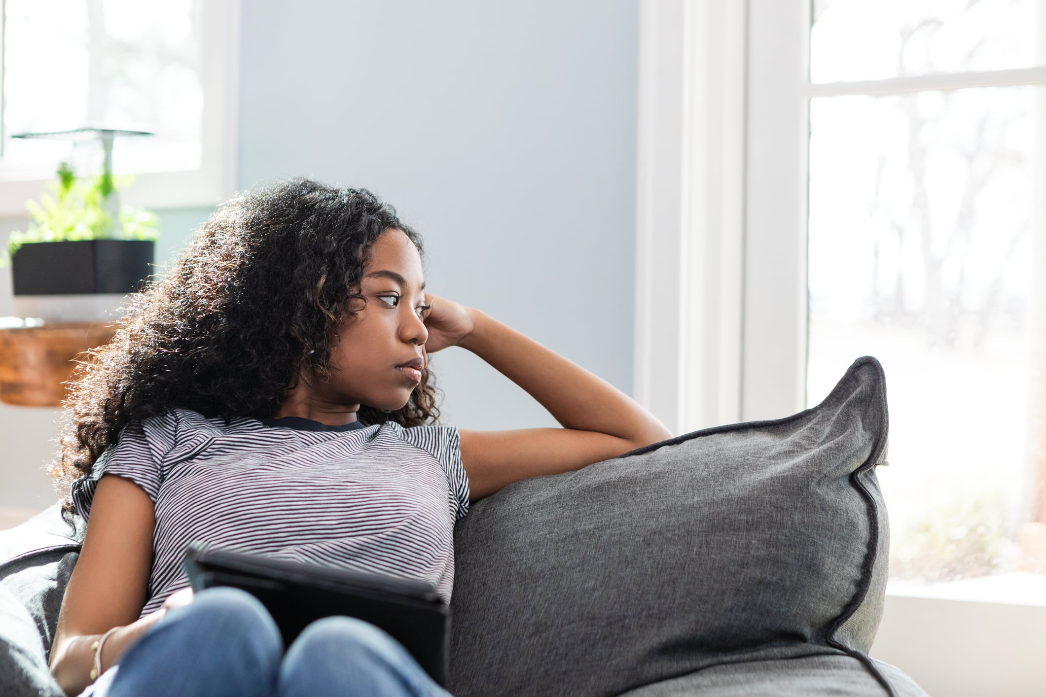 Teenage Girl Contemplating, Sitting on Sofa Indoors